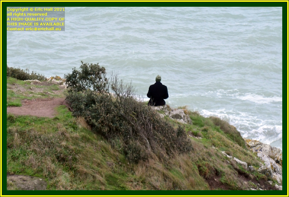 person sitting on rocks pointe du roc Granville Manche Normandy France photo Eric Hall december 2021